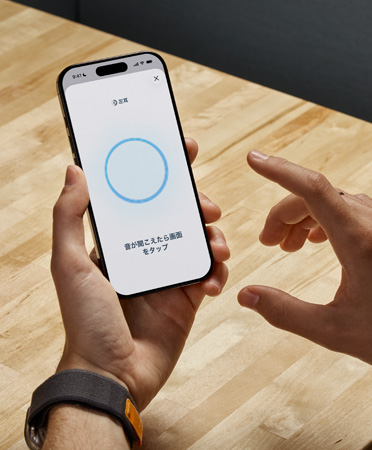 iPhoneでヒアリングチェックをしている人物