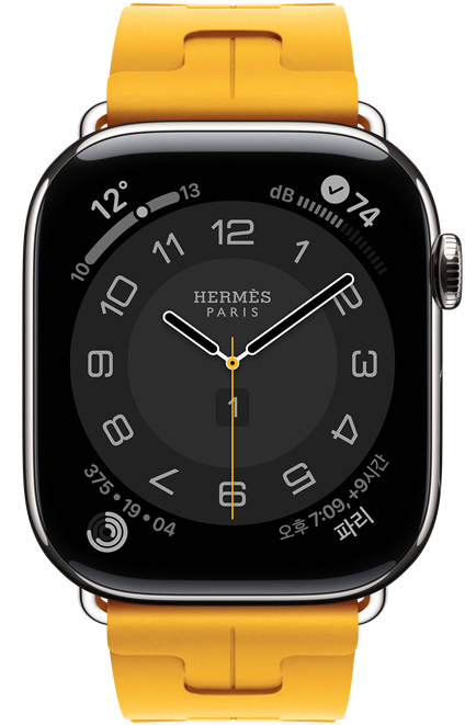 Apple Watch Hermès Series 11 Circulaire 아날로그 시계 페이스 (시, 분, 초침, 컴플리케이션: 날씨, 활동 링, 파리 시간, 노이즈), 실버 색상, 티타늄 케이스가 있고 오른쪽 옆면 외관에 Digital Crown이 보이는 성형 고무 소재의 죤(카나리 옐로) 색상 Kilim 싱글 투어 밴드와 페어링되어 있는 모습