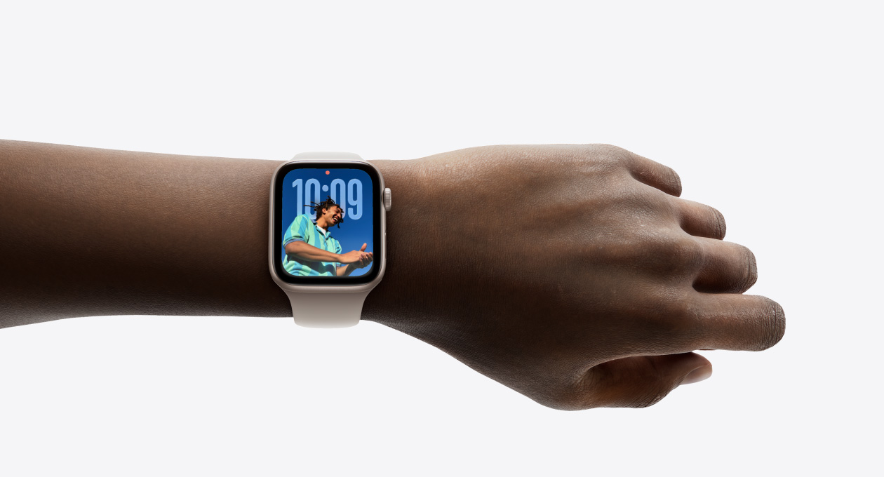 Close-up of Apple Watch in Rose Gold with rubber strap on a person’s wrist, showing new Liquid Glass design