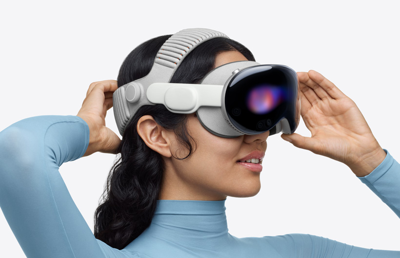 Person wearing Apple Vision Pro, assembled with Dual Knitted Band, upper band spans across the top of the head, one hand placed on lower back band behind head, other hand placed on aluminium alloy frame