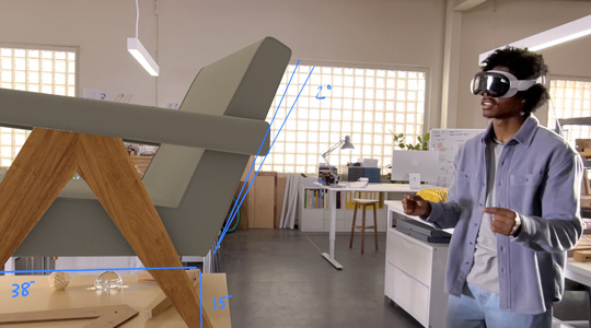 A designer wearing Apple Vision Pro measures a 3D projection of a chair, using a pinching motion with their hands to twist the chair