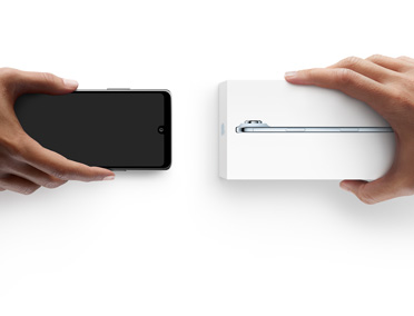 Hands exchanging phones, Android on the left without a box, on the right is a new iPhone 17 Pro in box